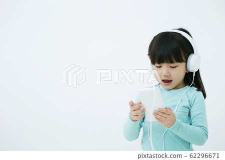 在智能手機的女孩聽的音樂有在白色背景隔絕的耳機的 在智能手機的女孩聽的音樂有在白色背景隔絕的耳機的 62296671