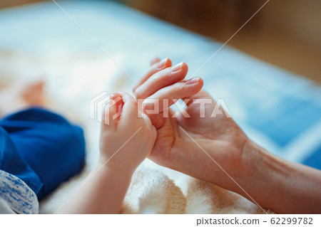 Close-up of baby's hand holding mother Close-up of baby's hand holding mother 62299782