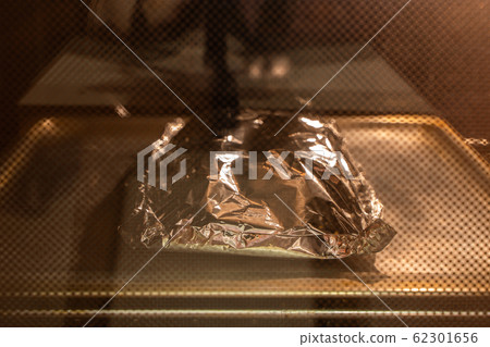 Food covered with foil on the pan inside oven Food covered with foil on the pan inside oven 62301656