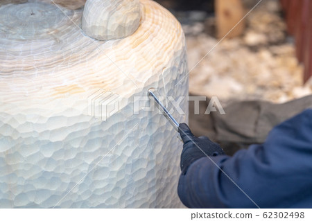 Wood carver working on a large sculpture of Winnie the Pooh Wood carver working on a large sculpture of Winnie the Pooh 62302498