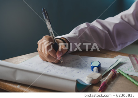 Hand and writing during the exam of a student. Hand and writing during the exam of a student. 62303933