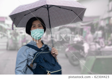 Elderly women in asia Wear a Corona Virus and minute dust pm 2.5 protection mask Walking and holding umbrellas around the market Elderly women in asia Wear a Corona Virus and minute dust pm 2.5 protection mask Walking and holding umbrellas around the market 62304423