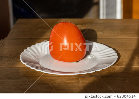 Tasty Mature orange persimmon fruit on white plate 62304514