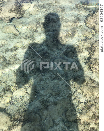 Man Shadow under water on sand shore Man Shadow under water on sand shore 62304547