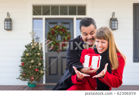 Young Mixed Race Couple Exchanging Gift On Front a House Young Mixed Race Couple Exchanging Gift On Front a House 62306859