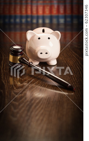 Gavel and Piggy Bank on Wooden Table With Law Books Behind Books Behind Gavel and Piggy Bank on Wooden Table With Law Books Behind Books Behind 62307346