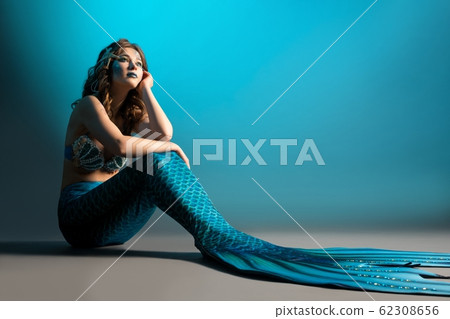 Woman in mermaid image sitting on the floor shot Woman in mermaid image sitting on the floor shot 62308656