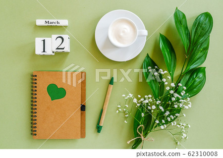 Wooden cubes calendar March 12. Notepad, cup of coffee, bouquet flowers on green background. Concept hello spring Top view Flat lay Mock up 62310008