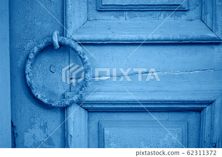 Old vintage door with peeling paint and a rusty handle in the form of a ring. Classic blue. The 2020 trend. 62311372
