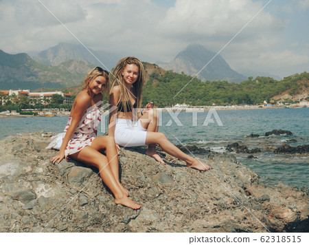 Young women sitting on the rocks by the sea 62318515