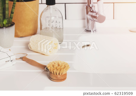 Natural material dish washing brush on white countertop close-up. Natural material dish washing brush on white countertop close-up. 62319509