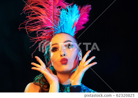 Beautiful young woman in carnival and masquerade costume in colorful neon lights on black background 62320825