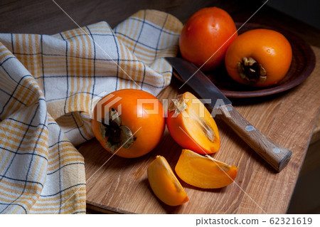 Whole ripe persimmon and sliced fruit on a wooden Whole ripe persimmon and sliced fruit on a wooden 62321619