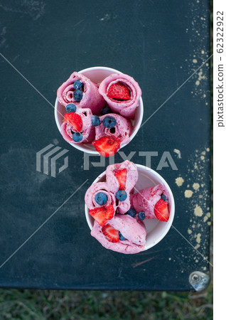 Rolls of natural ice cream in a cups. Two cups with ice cream and berries. Rolls of natural ice cream in a cups. Two cups with ice cream and berries. 62322922