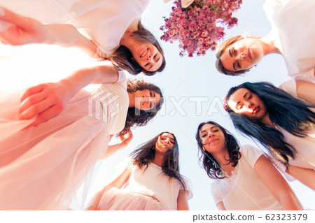 Happy young bridesmaids looking down together, bottom view Happy young bridesmaids looking down together, bottom view 62323379
