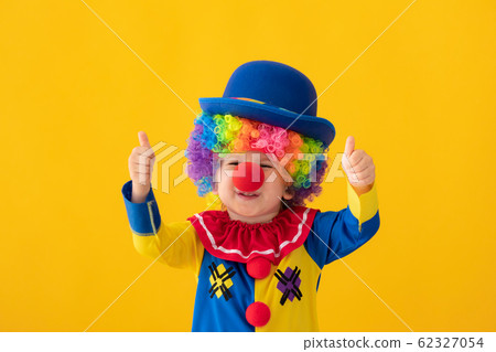 Funny kid clown playing against yellow background 62327054