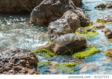 Pure clear water on a wild stone beach in the sea Pure clear water on a wild stone beach in the sea 62327551