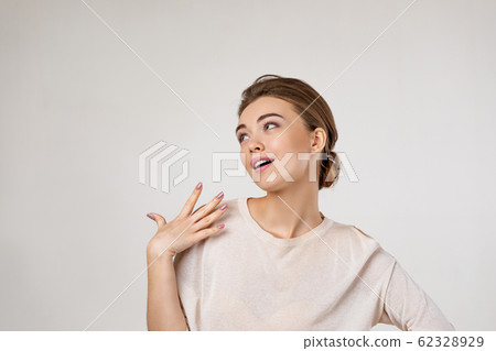 Portrait of young surprised beautiful woman screaming with shocked facial expression and looking to the side on gray background Portrait of young surprised beautiful woman screaming with shocked facial expression and looking to the side on gray background 62328929