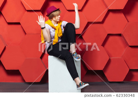 The girl in the red hat sits near the red wall The girl in the red hat sits near the red wall 62330348