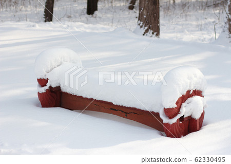 a park bench covered with a large layer of snow a park bench covered with a large layer of snow 62330495