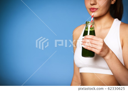 Delighted female with green smoothie laughing 62330625