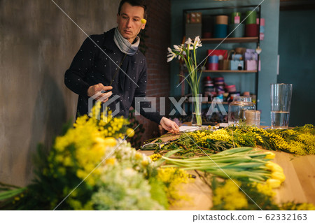 Male make spring bouquet. Gardener's in the flower shop make bouquet. Lifestyle flower shop. Beautiful flower composition of yellow flowers Male make spring bouquet. Gardener's in the flower shop make bouquet. Lifestyle flower shop. Beautiful flower composition of yellow flowers 62332163