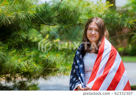 Smiling cute girl wrapped in american flag. Smiling cute girl wrapped in american flag. 62332307