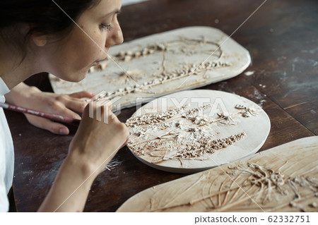 Woman brush the relief pattern obtained from the mold for casting clay products 62332751
