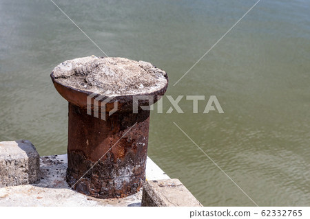 an old iron bollard weathered stands on the edge an old iron bollard weathered stands on the edge 62332765
