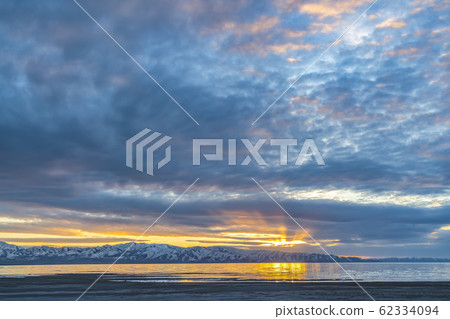 Lake and snow capped mountain underneath a sky 62334094