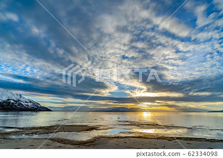Striking cloudy sky over a calm lake that reflects 62334098