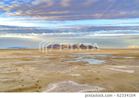 Sandy shore of a lake and distant rugged mountain 62334104