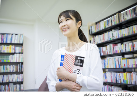 A woman studying for qualification (The cover of the reference book is a dummy created for Pixta photography) 62338160