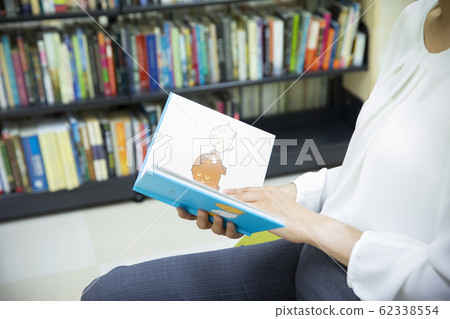 A woman choosing a picture book (picture book is a dummy created for Pixta) A woman choosing a picture book (picture book is a dummy created for Pixta) 62338554