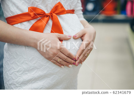 Heart symbol folded from the hands. a pregnant woman is stroking her stomach. Copy space. Healthy lifestyle concept, IVF, mother's day, international women's day, Valentine's day 62341679