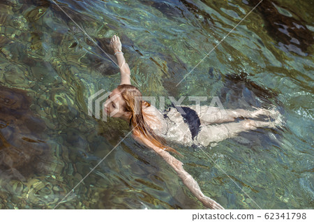 Beautiful slim young woman in a black bikini 62341798