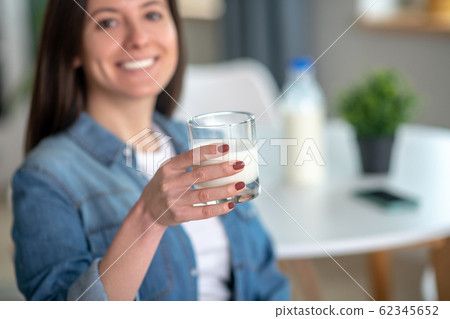 Woman holding a glass of tasty milk 62345652