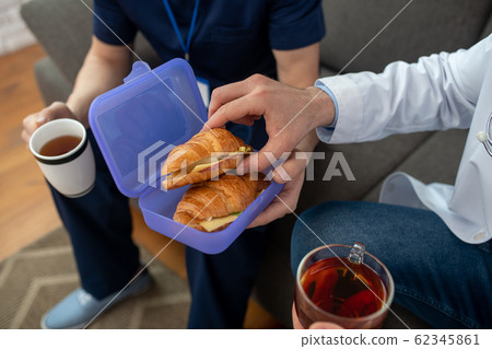 Two people hsharing sandwiches for breakfast and having tea 62345861