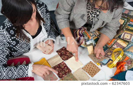 seamstress and her apprentice choose fabric for 62347603
