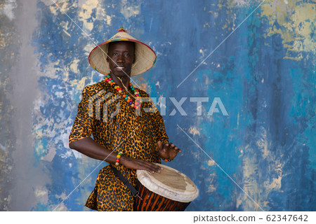 African man in traditional clothes playing djembe drum 62347642