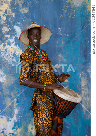 African man in traditional clothes playing djembe drum 62347643