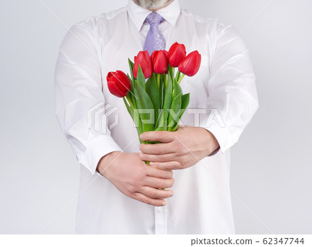 adult man in a white shirt and a lilac tie holding 62347744