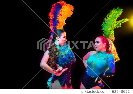 Beautiful young women in carnival and masquerade costume in colorful neon lights on black background Beautiful young women in carnival and masquerade costume in colorful neon lights on black background 62348631