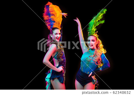 Beautiful young women in carnival and masquerade costume in colorful neon lights on black background Beautiful young women in carnival and masquerade costume in colorful neon lights on black background 62348632