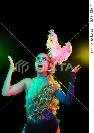Beautiful young woman in carnival and masquerade costume in colorful neon lights on black background Beautiful young woman in carnival and masquerade costume in colorful neon lights on black background 62348664