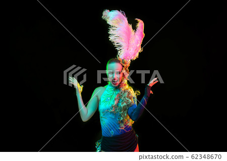 Beautiful young woman in carnival and masquerade costume in colorful neon lights on black background Beautiful young woman in carnival and masquerade costume in colorful neon lights on black background 62348670