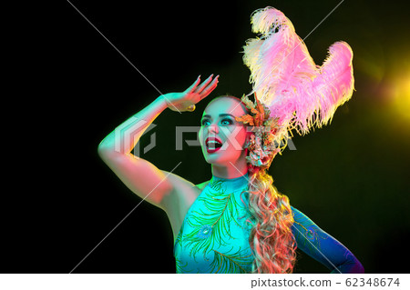Beautiful young woman in carnival and masquerade costume in colorful neon lights on black background Beautiful young woman in carnival and masquerade costume in colorful neon lights on black background 62348674