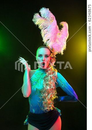 Beautiful young woman in carnival and masquerade costume in colorful neon lights on black background Beautiful young woman in carnival and masquerade costume in colorful neon lights on black background 62348675