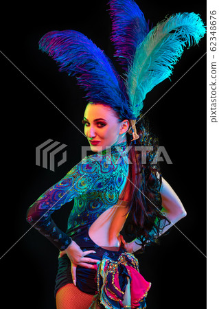 Beautiful young woman in carnival and masquerade costume in colorful neon lights on black background Beautiful young woman in carnival and masquerade costume in colorful neon lights on black background 62348676