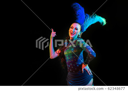 Beautiful young woman in carnival and masquerade costume in colorful neon lights on black background Beautiful young woman in carnival and masquerade costume in colorful neon lights on black background 62348677